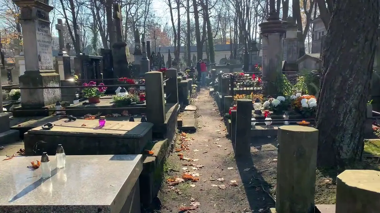 Old gravestones and paths with visitors in a Polish cemetery in autumn