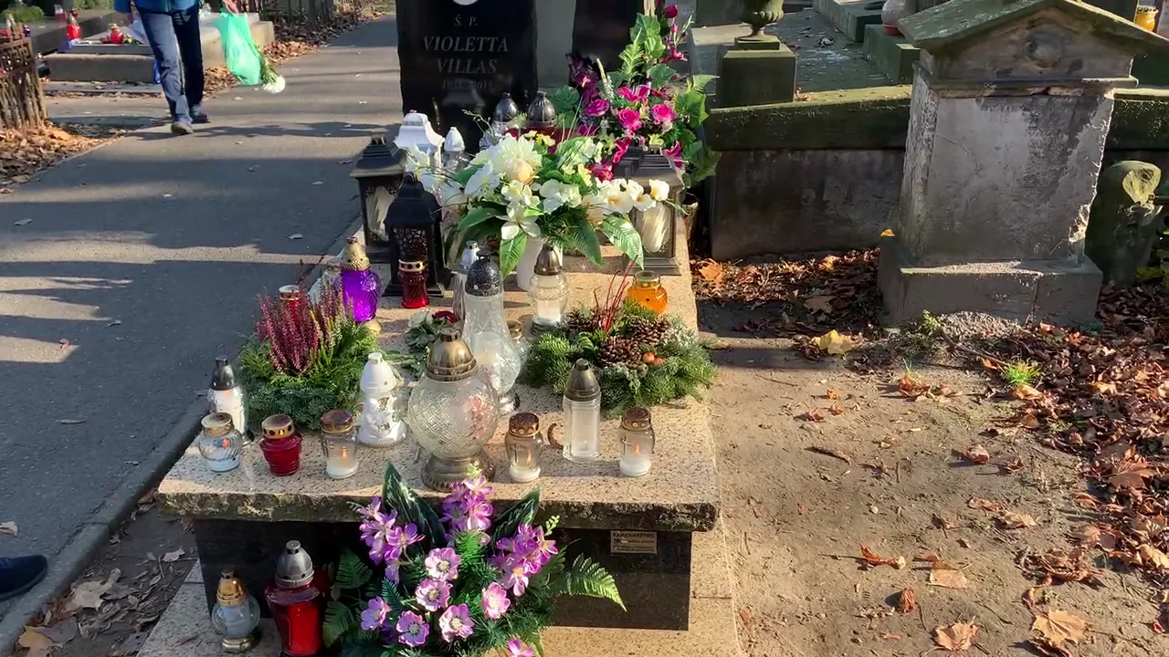 Decorated cemetery grave with purple and white flowers and glass grave candles