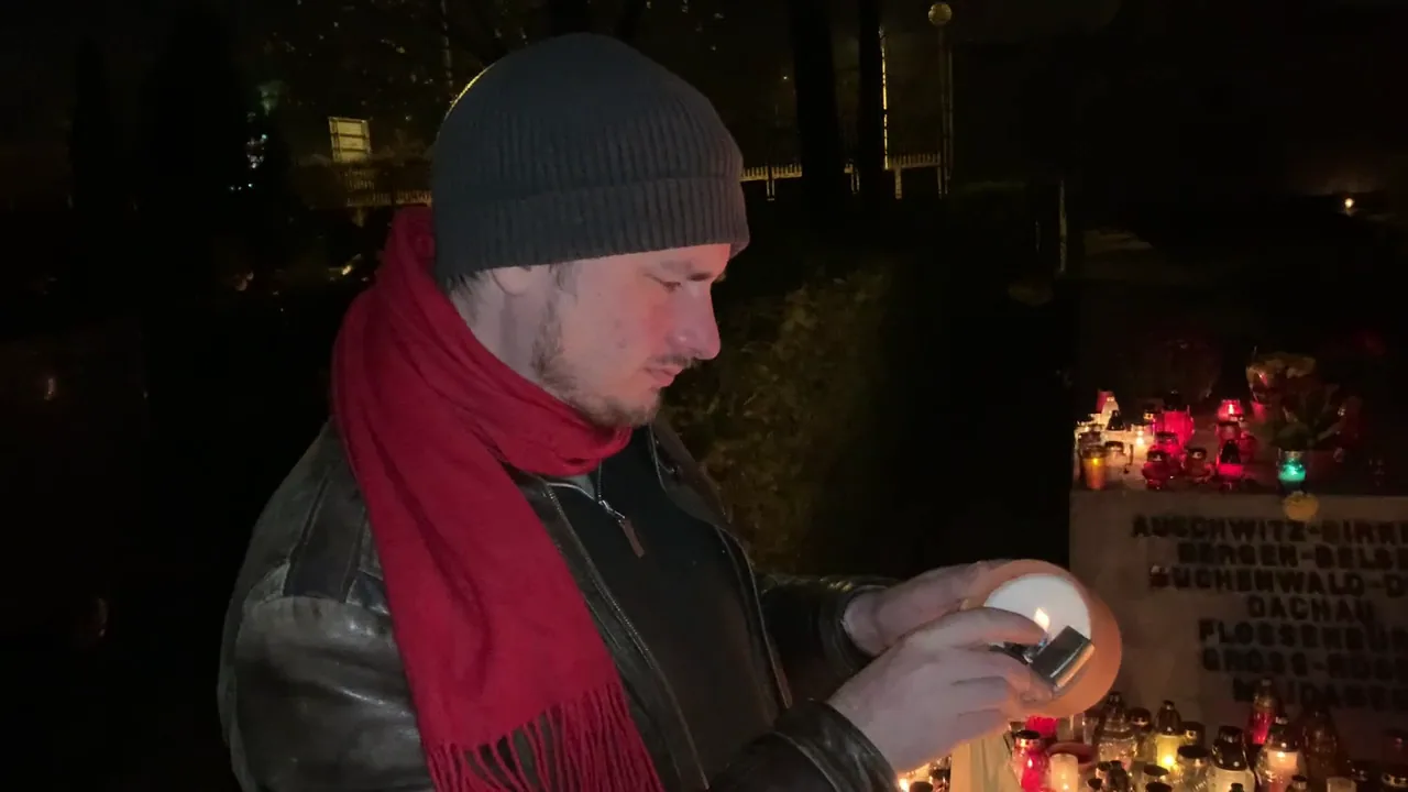 The author lighting a candle in a Polish cemetery at night