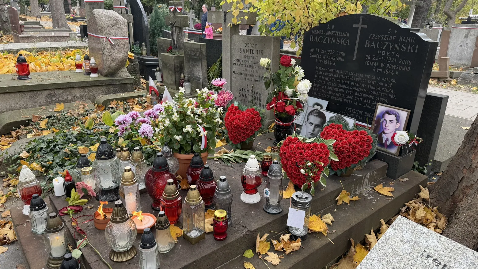The shared grave of Krzysztof Kamil Baczyński and his wife Barbara, surrounded by flowers and candles.