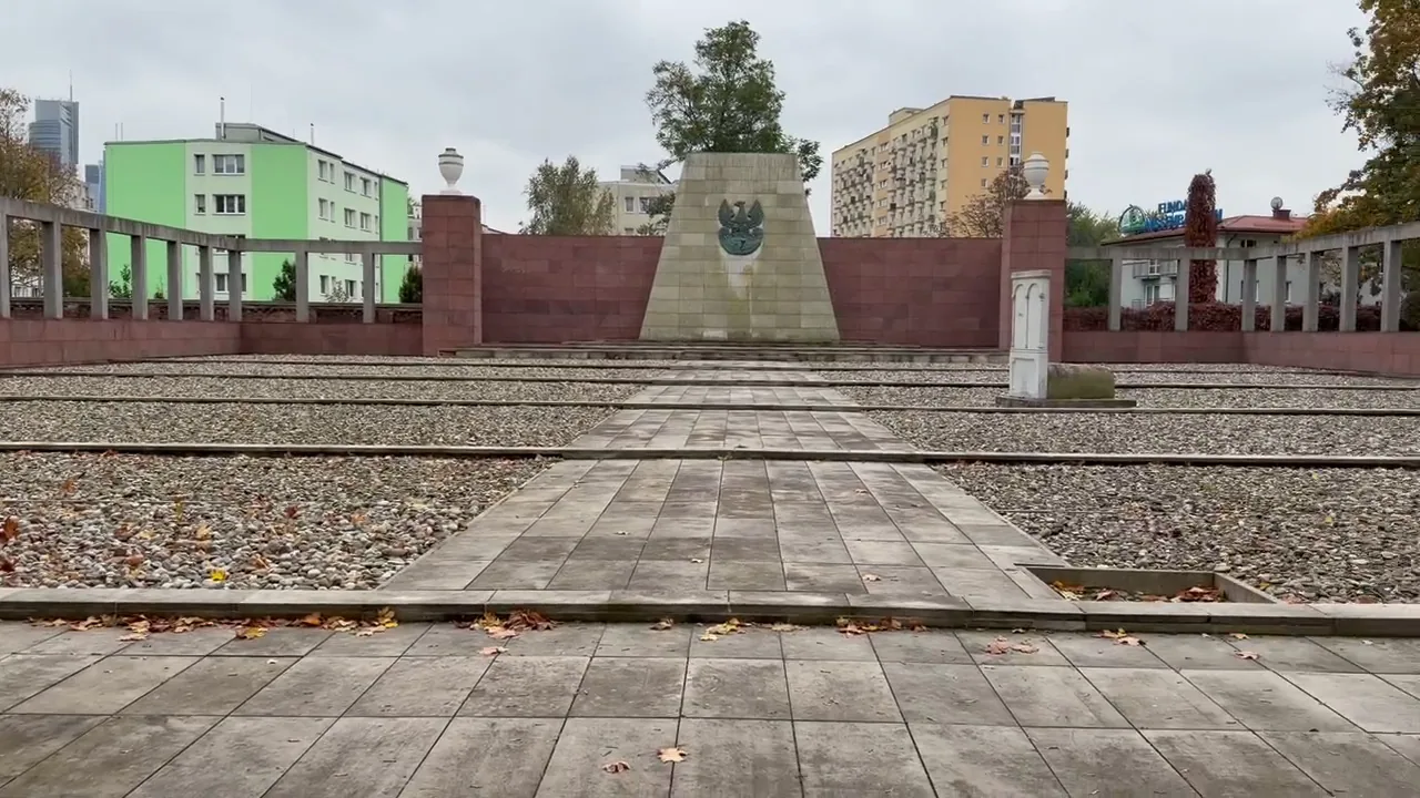 Open stone-paved memorial precinct with brick walls at Okopowa Jewish Cemetery