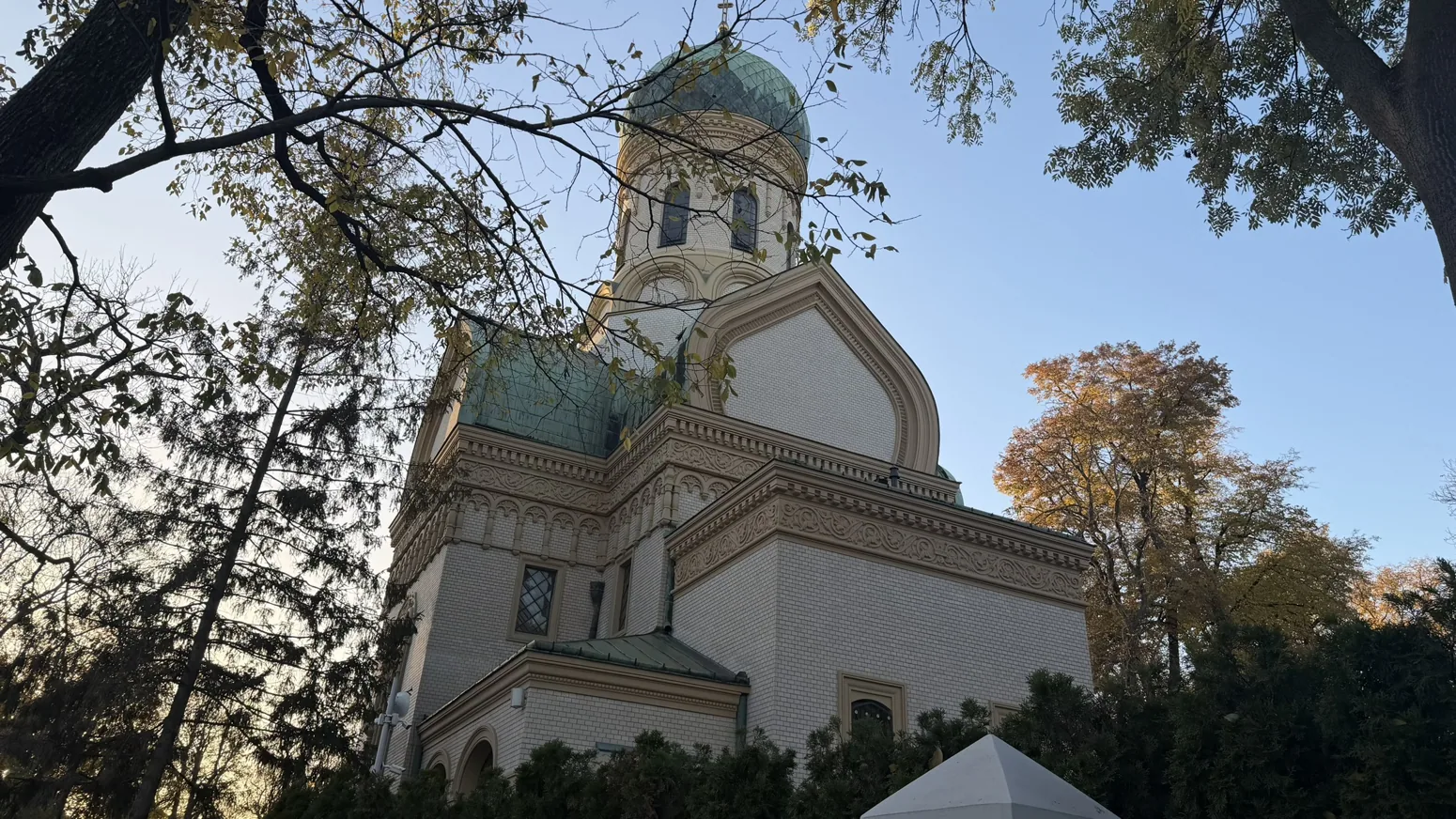 Photograph of Warsaw Orthodox Cemetery: The Church of St John Climacus and autumn trees seen from within the cemetery.