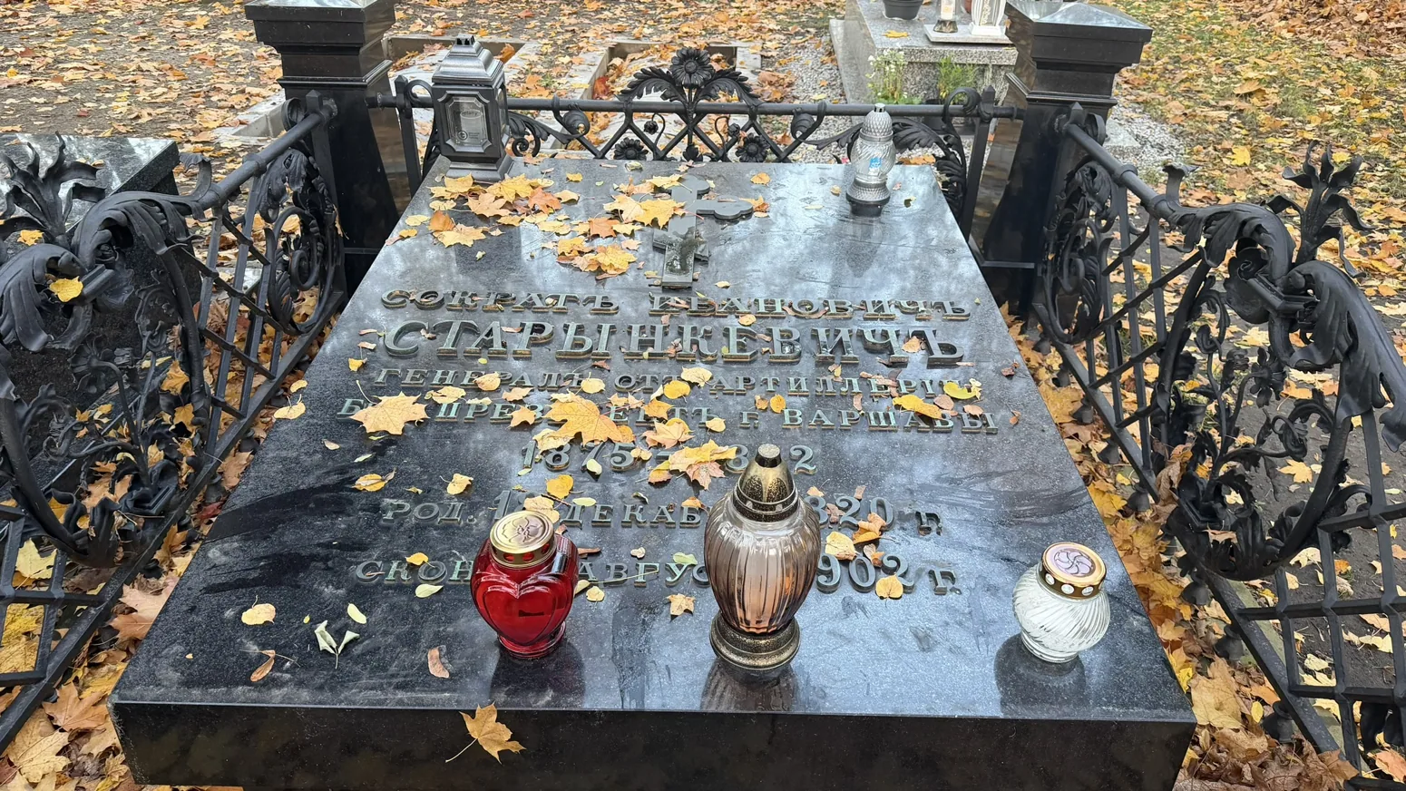 Photograph of Warsaw Orthodox Cemetery: A close-up of a grave with candles and inscriptions; precise occupant not independently verified.