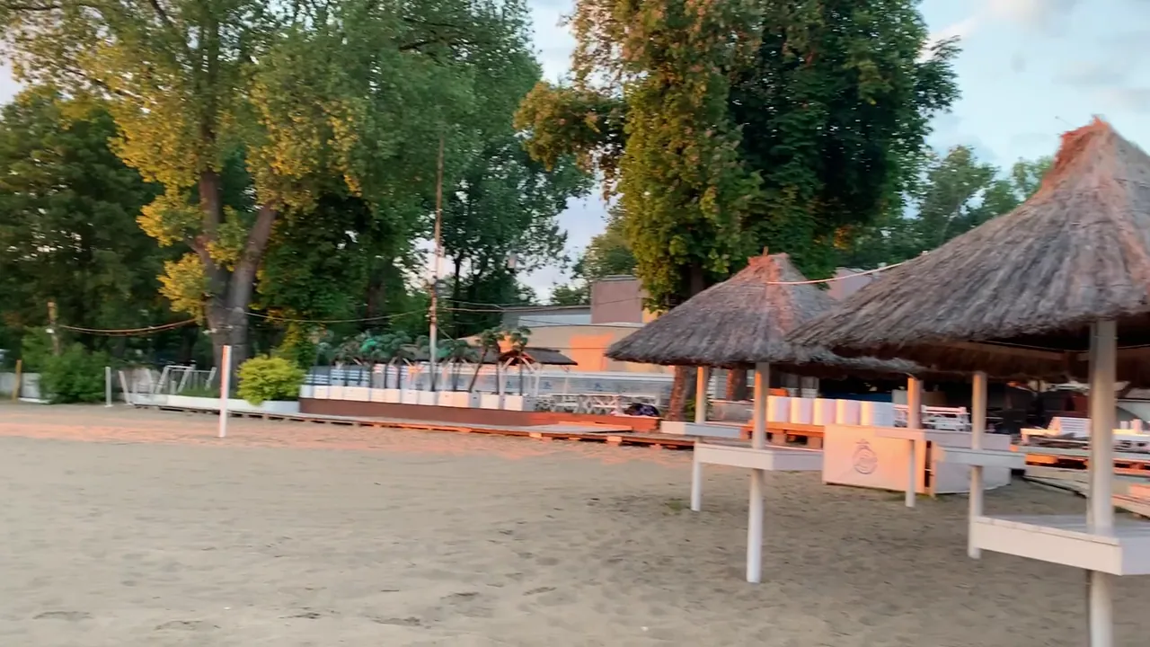 Sandy riverside beach with shaded outdoor shelters