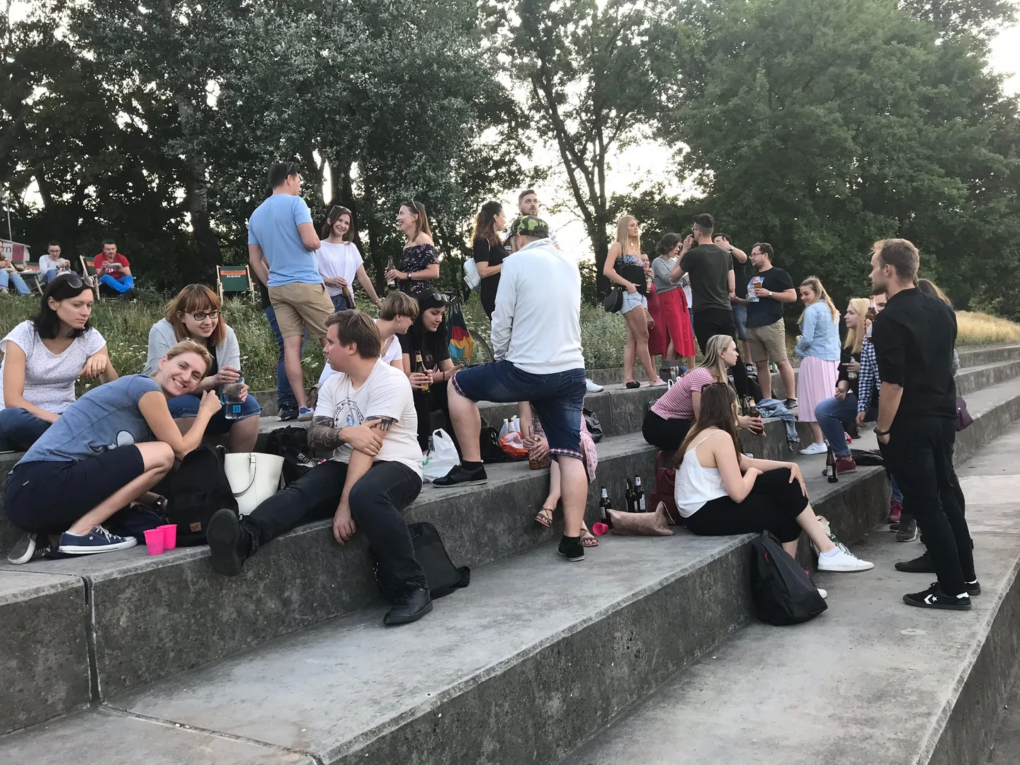 Friends gathering for a birthday celebration on riverside steps in Warsaw